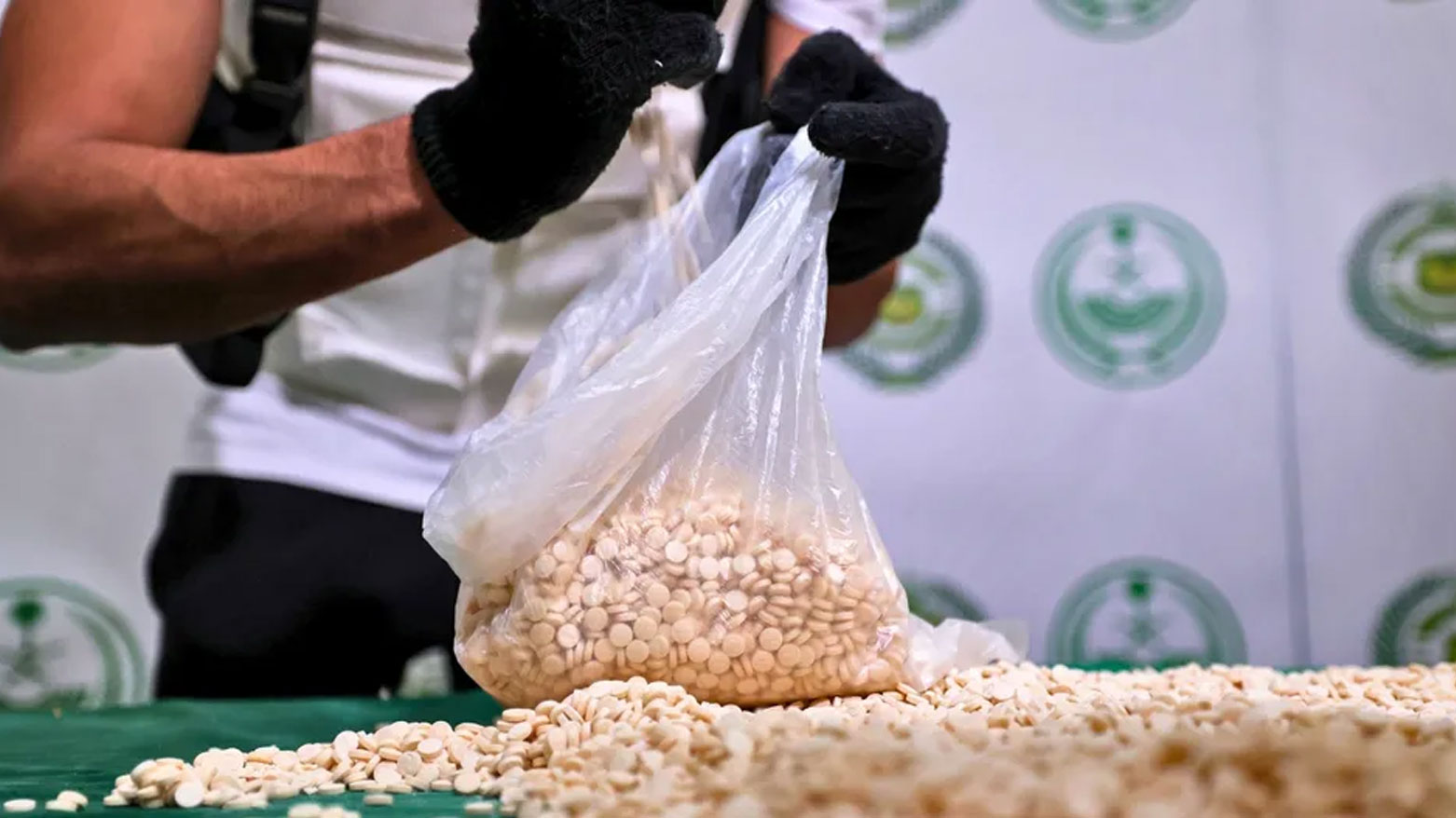 An Iraqi police officer inspecting a plastic bag full of captagon pills. (Photo: Iraqi Media)