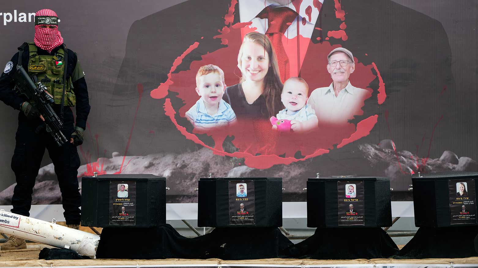 A militant stands next to the coffins containing the bodies of hostages, from right to left, Shiri Bibas, her two children, Ariel and Kfir and Oded Lifshitz, who was 83 when he was abducted, in Khan Younis, southern Gaza, Feb. 20, 2025. (Photo: AP)