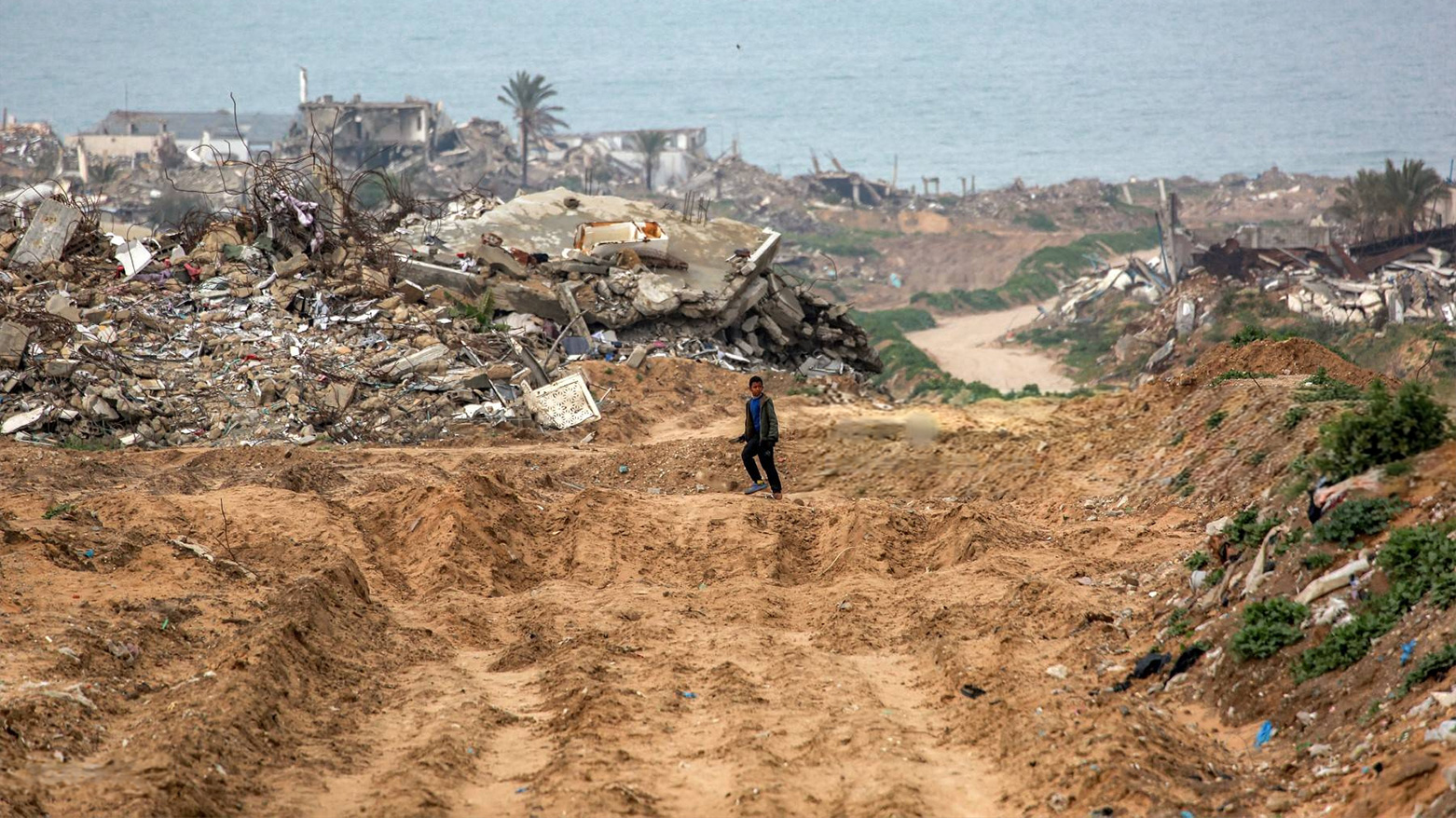A boy walks along a destroyed road past collapsed buildings in the west of Beit Lahia in the northern Gaza Strip on Feb. 11, 2025. (Photo: AFP)