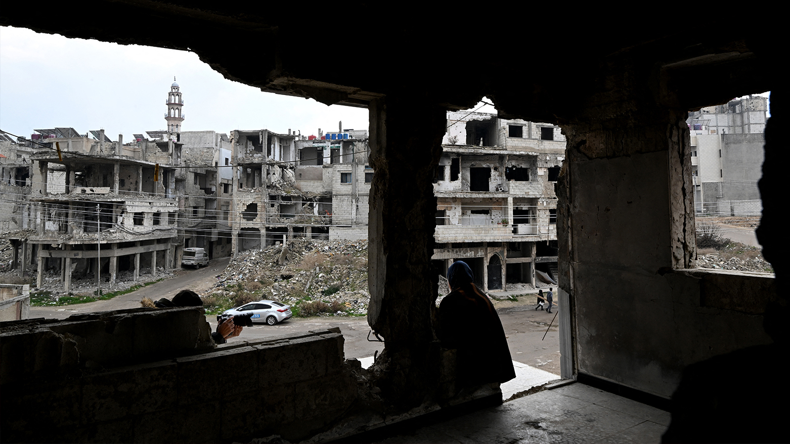 Displaced Syrian, looks at the destruction in her neighbourhood from her damaged apartment in Homs, Syria on Feb. 10, 2025. (Photo: AFP)