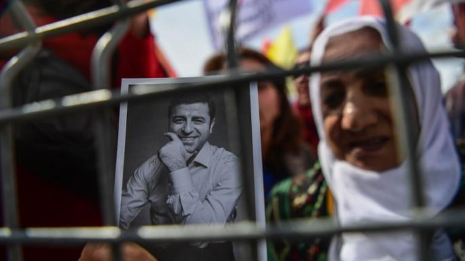 A woman standing behind a fence holds a portrait of Selahattin Demirtas, in Istanbul on Mar. 21, 2018. (Photo: AFP)