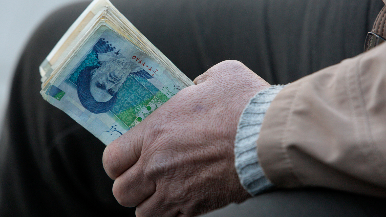 An Iranian street money exchanger holds Iranian banknotes. (Photo: AP)