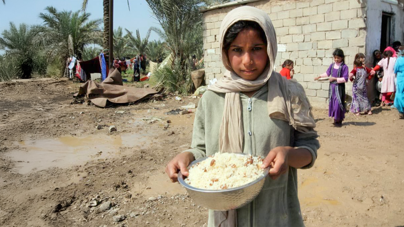 A displaced Iraqi girls poses for a photo holding a bowel of rice on March 20, 2015 at a camp for internally displaced persons (IDP) in Baghdad. (Photo: AFP)