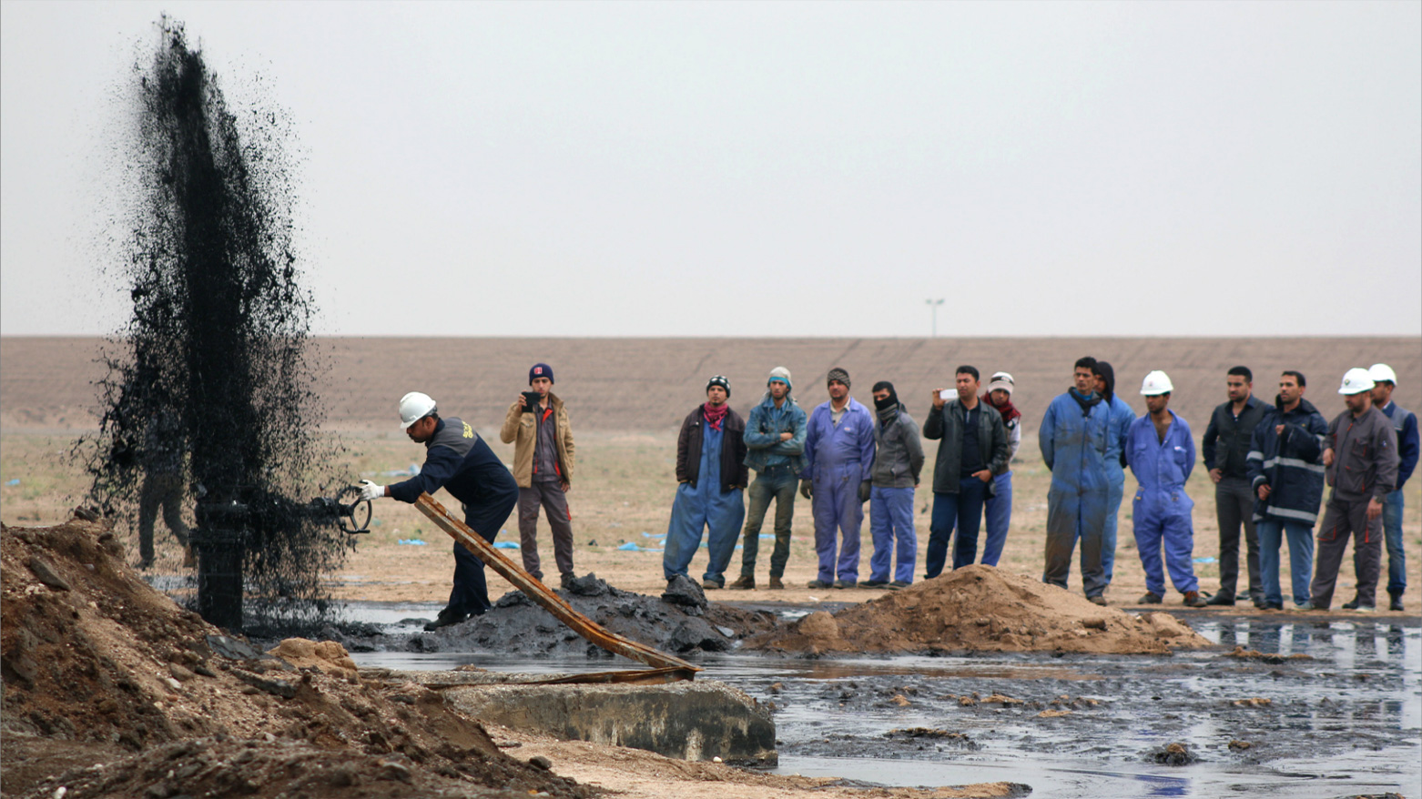 Workers from the South Oil Company watch on as a pipeline ejects oil in Tuba oilfield West of Iraq's second largest city of Basra on February 19, 2015. (Photo: AFP)