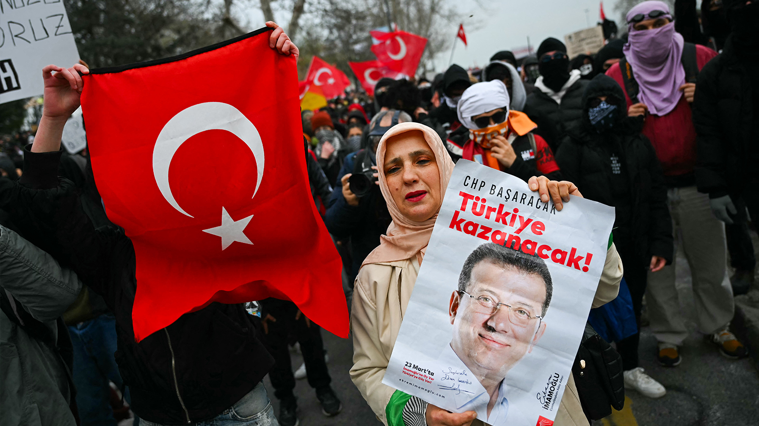 Protesters hold signs and Turkish flags during a rally in support of Istanbul's arrested mayor in Istanbul Municipality, on March 23, 2025.(Photo: AFP)