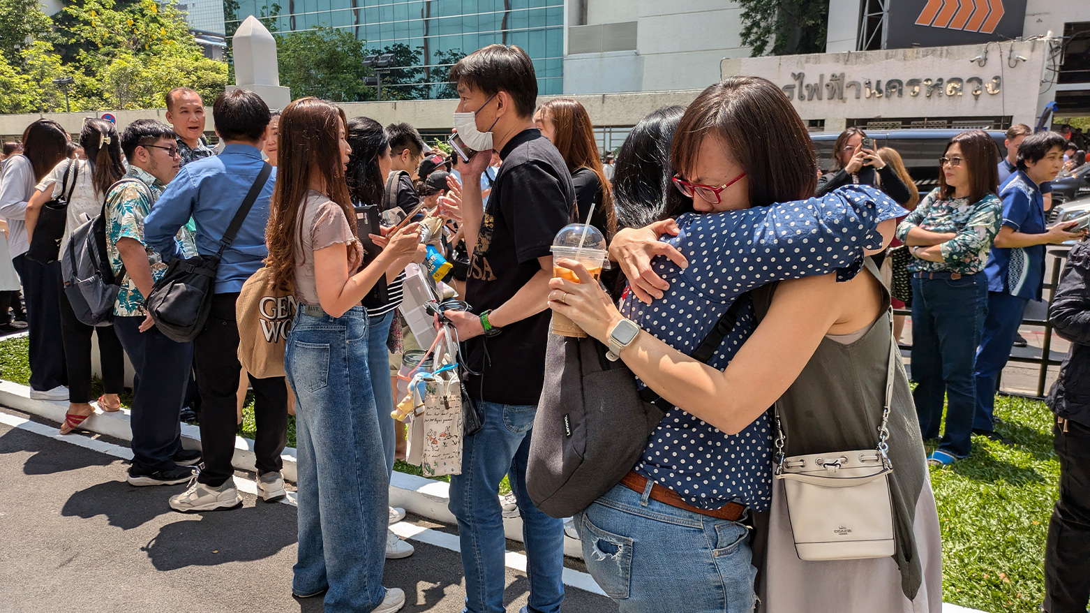 People stand outside an office building in Bangkok on March 28, 2025 after an earthquake. (Photo: AFP)