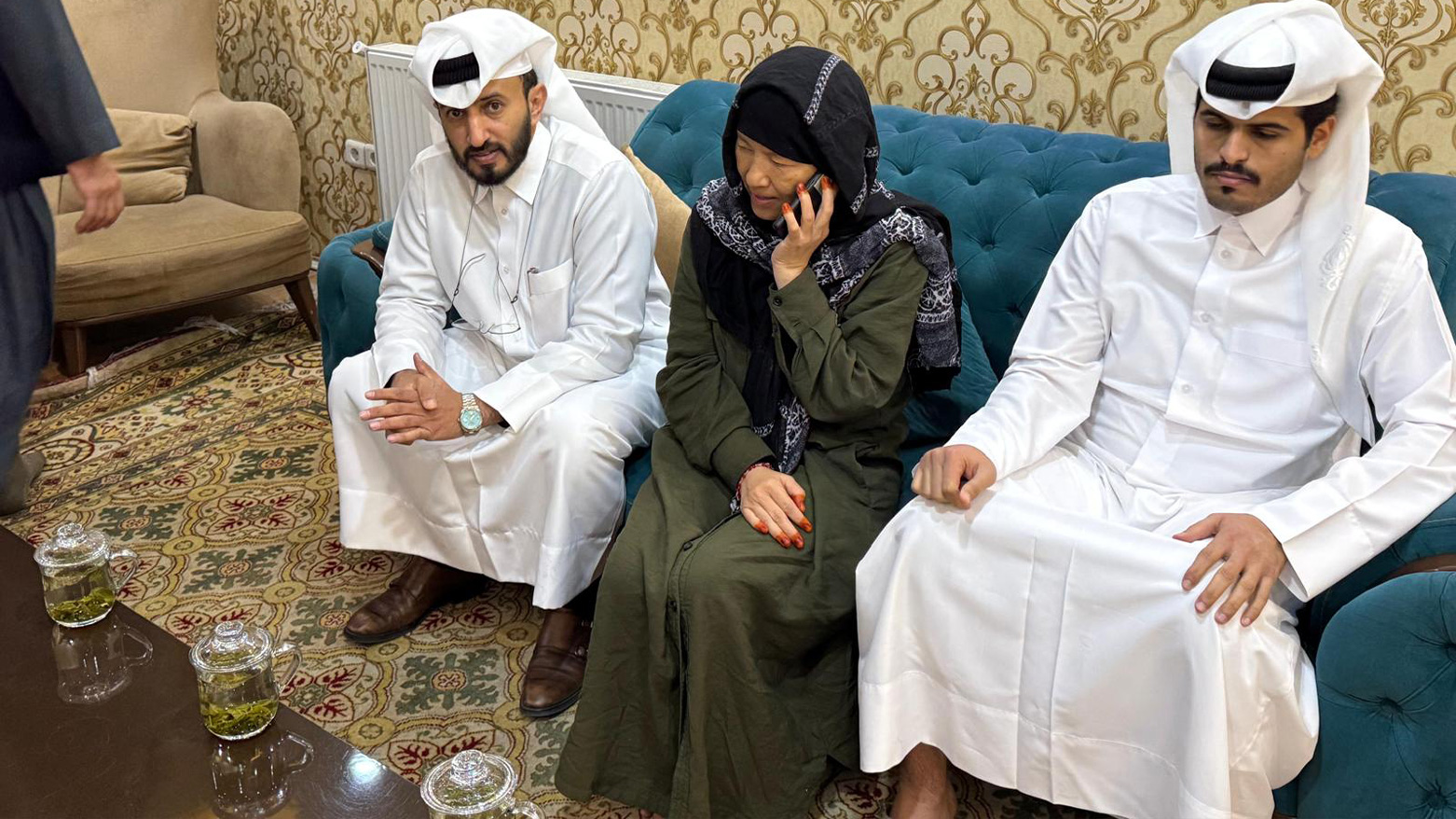 Faye Hall (C) speaks on the phone after her release by the Taliban on March 29, 2025, alongside Qatar’s envoy Mirdef Alqashouti (L), in an image from a diplomatic source in Kabul. (Photo: AFP)