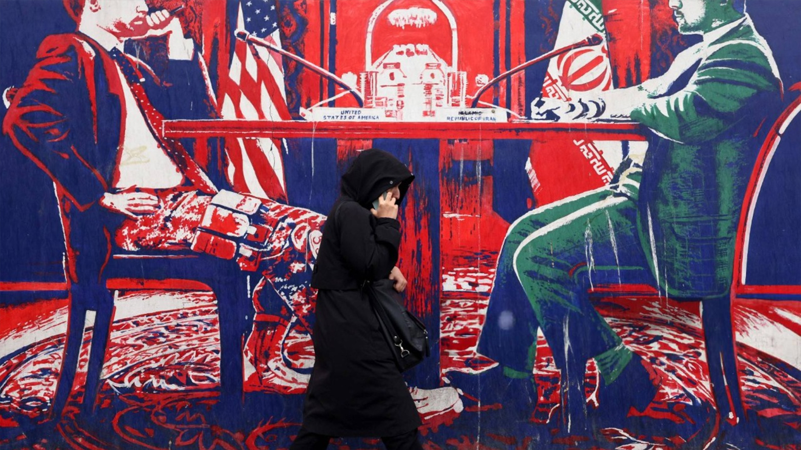 A woman walks past a mural painted on the outer wall of the former US Embassy in Tehran, dubbed the 'Den of Espionage', on March 8, 2025. (Photo: AFP)
