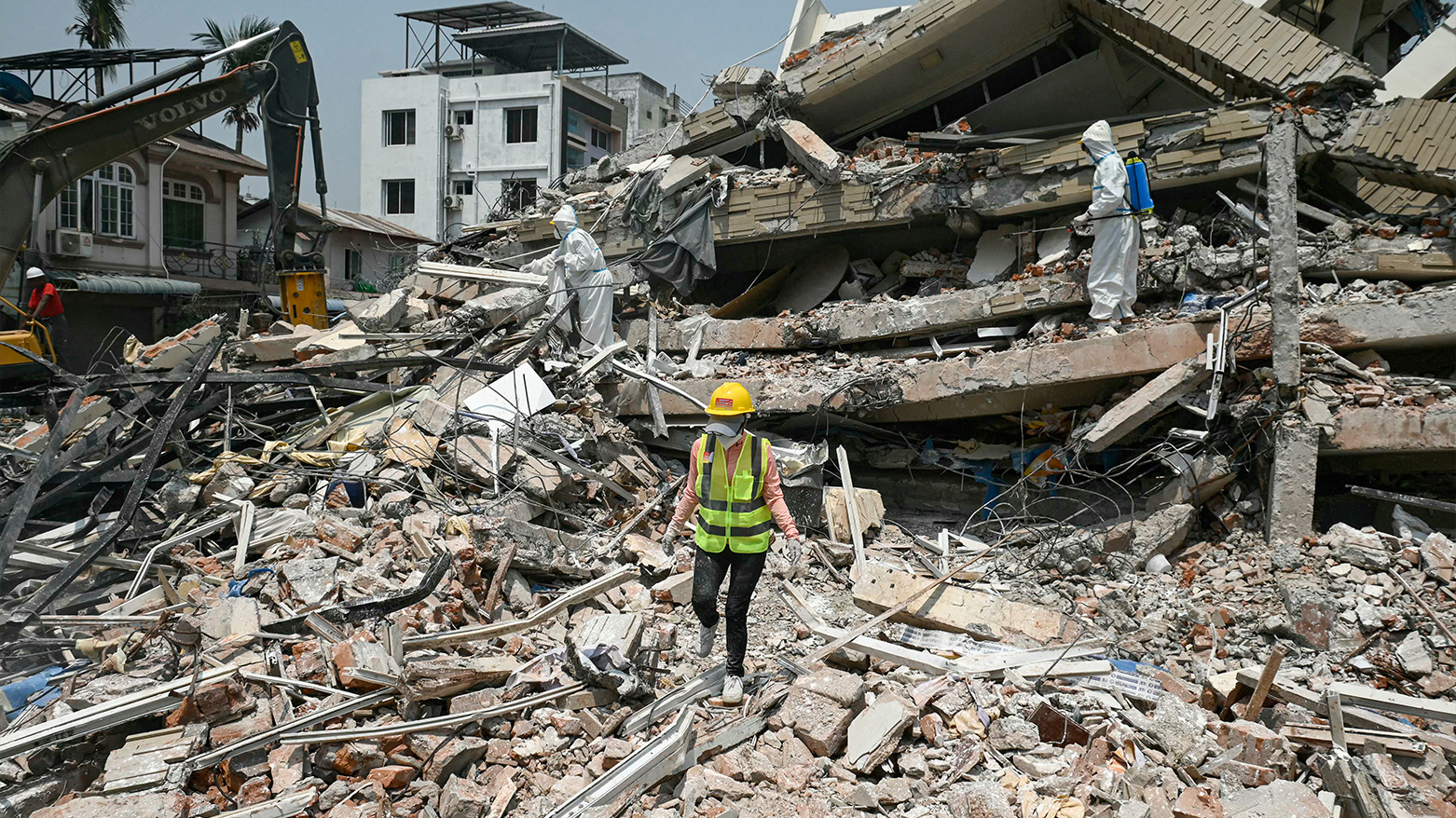 Workers wearing hazmat suit spray disinfectant to sterilise the rubble of a collapsed building in Mandalay on April 2, 2025. (Photo: AFP)