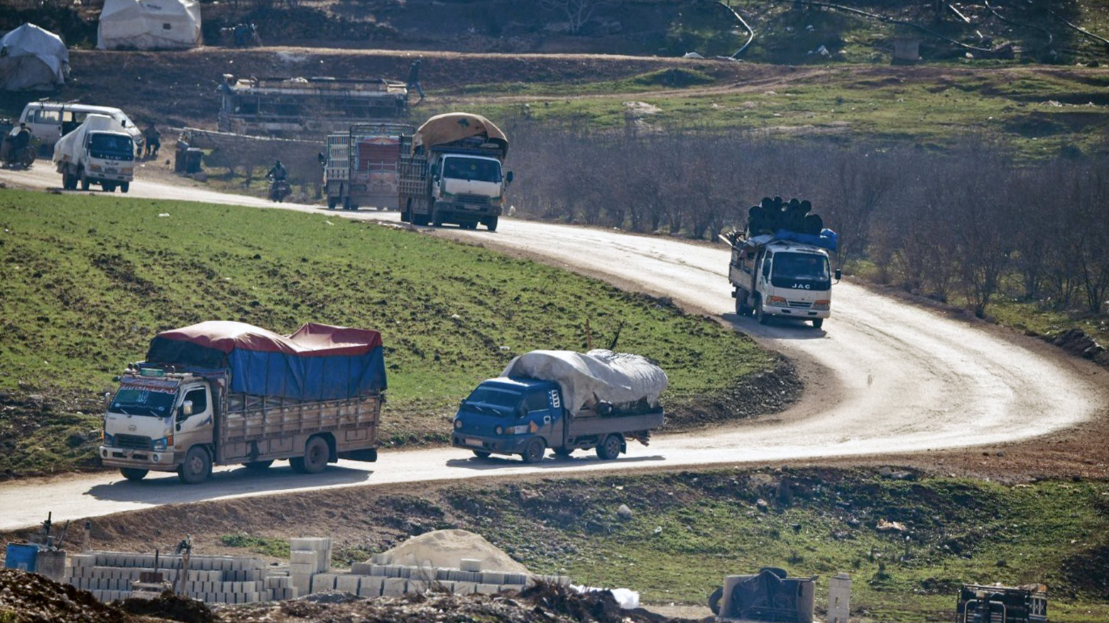 Vehicles carrying displaced Syrians pass by an internally-displaced persons (IDP) camp by Dayr Ballut near the Turkish border in the west of the northern province of Aleppo on Feb. 15, 2020. (Photo: AFP)