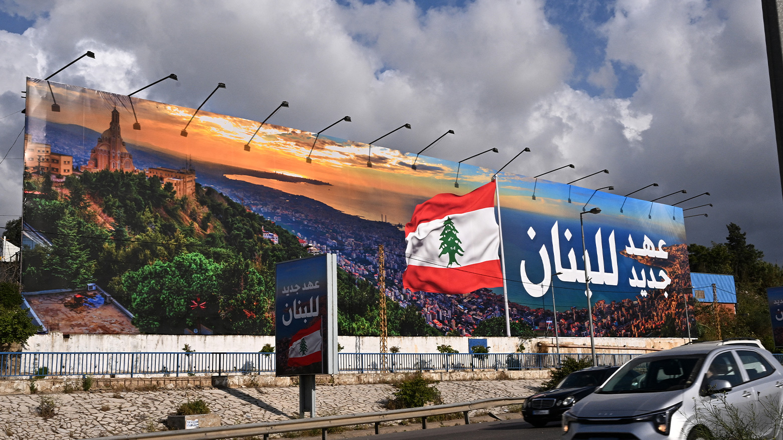 Commuters pass a new billboard reading "Lebanon, a new era" in Arabic, replacing a former Hezbollah display. (Photo: AFP)