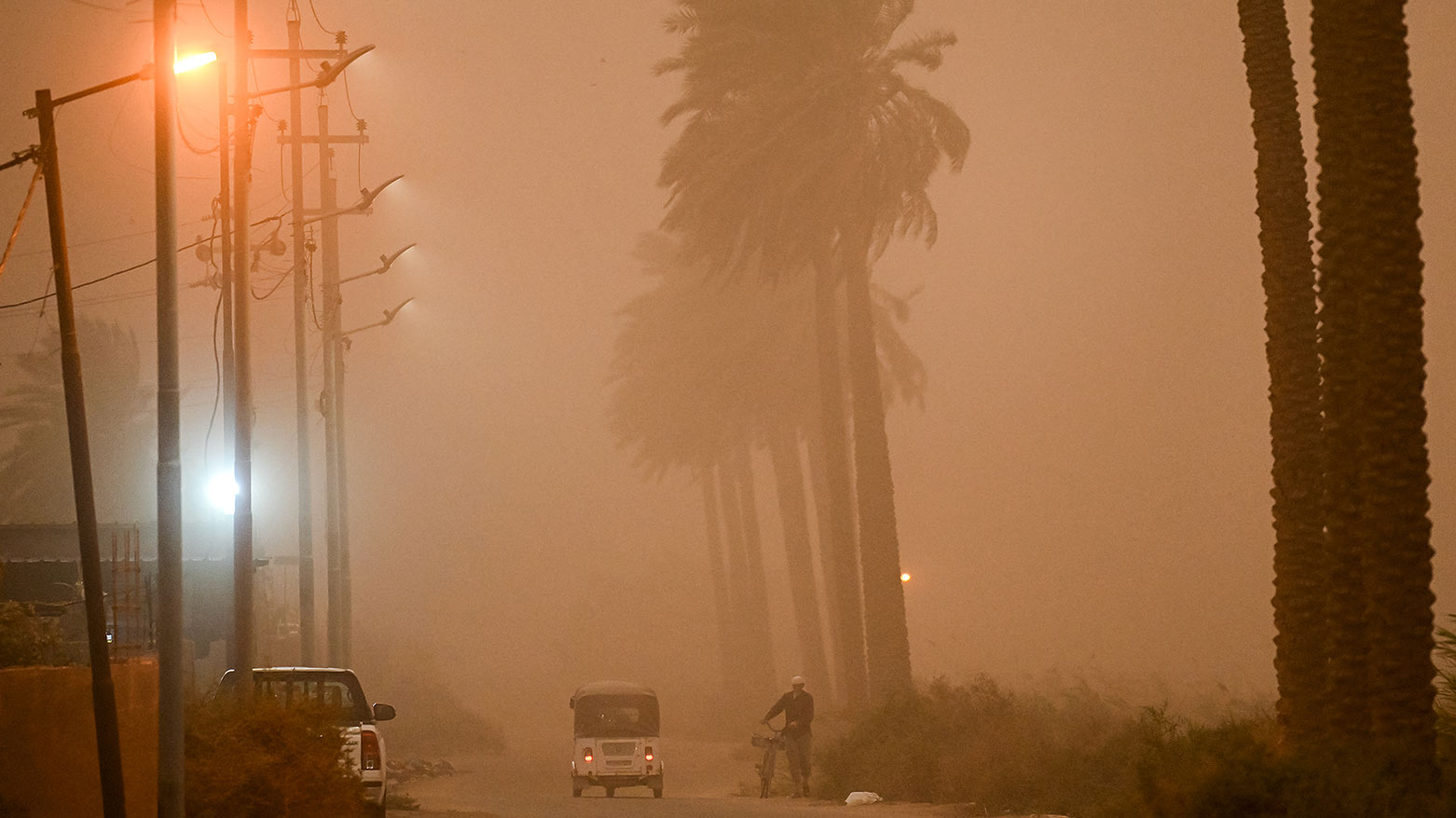 pedestrian struggles to breathe as he walks along the side of a road through low visibility conditions due to a massive dust storm in Iraq's central city of Najaf on April 14, 2025. (Photo: AFP)