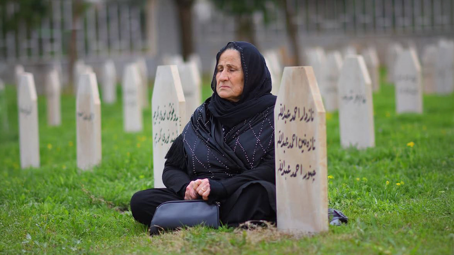 A Kurdish woman sits in silent grief among the graves of Halabja’s chemical weapons victims, visiting the resting place of a loved one she lost in the 1988 attack. (Photo: Kurdiatn24)
