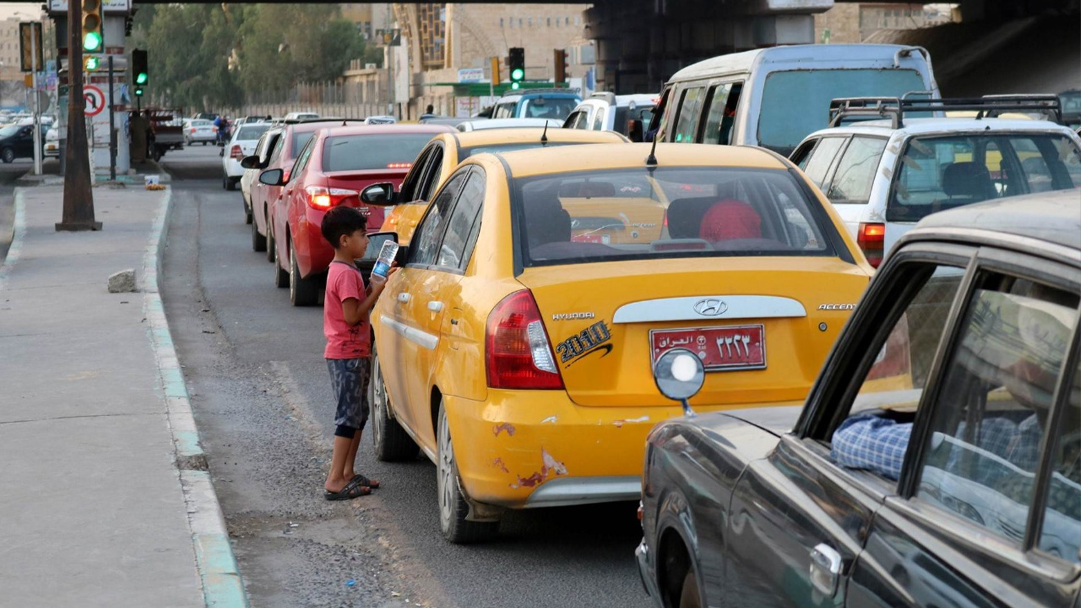 An Iraqi child peddlar sells water bottles to cars driving down a street in Mosul. (Photo: AFP)