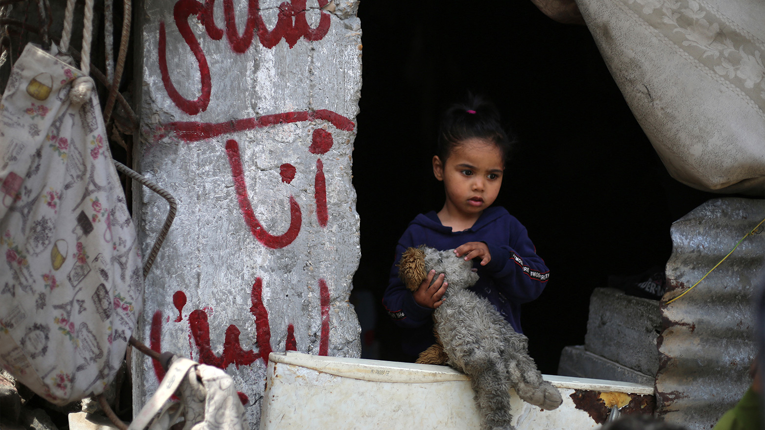 A girl stands by graffiti for children killed in Israeli strikes near their home in al-Bureij camp, Gaza, May 1, 2025. (Photo: AFP)