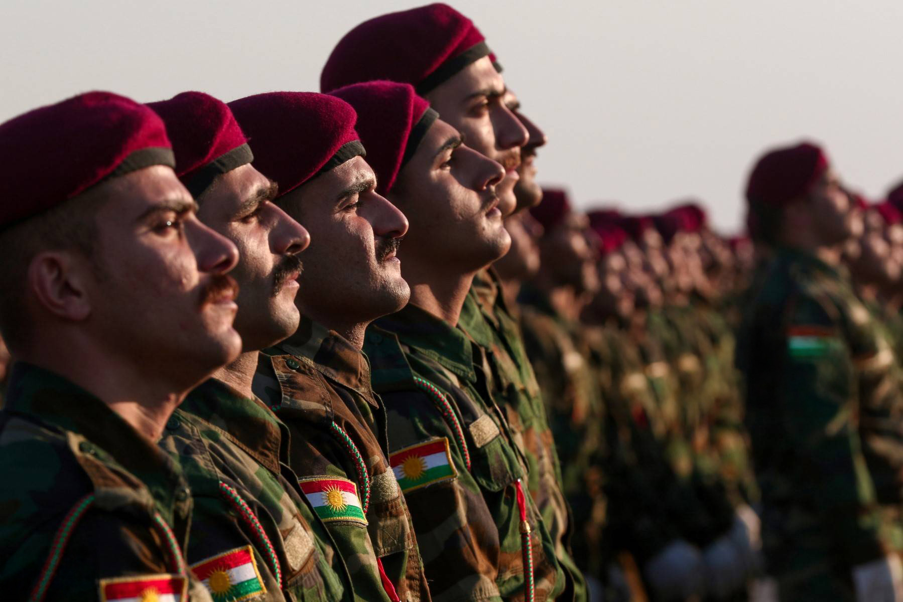 image shows Kurdish Peshmarga in uniform and maroon berets standing in formation, with the Kurdistan flag visible on their sleeves. (Photo: AFP)