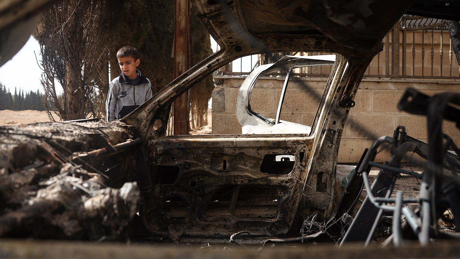 A boy checks a destroyed car following sectarian clashes in Ashrafiyat Sahnaya near Damascus on May 1, 2025. (Photo: AFP)