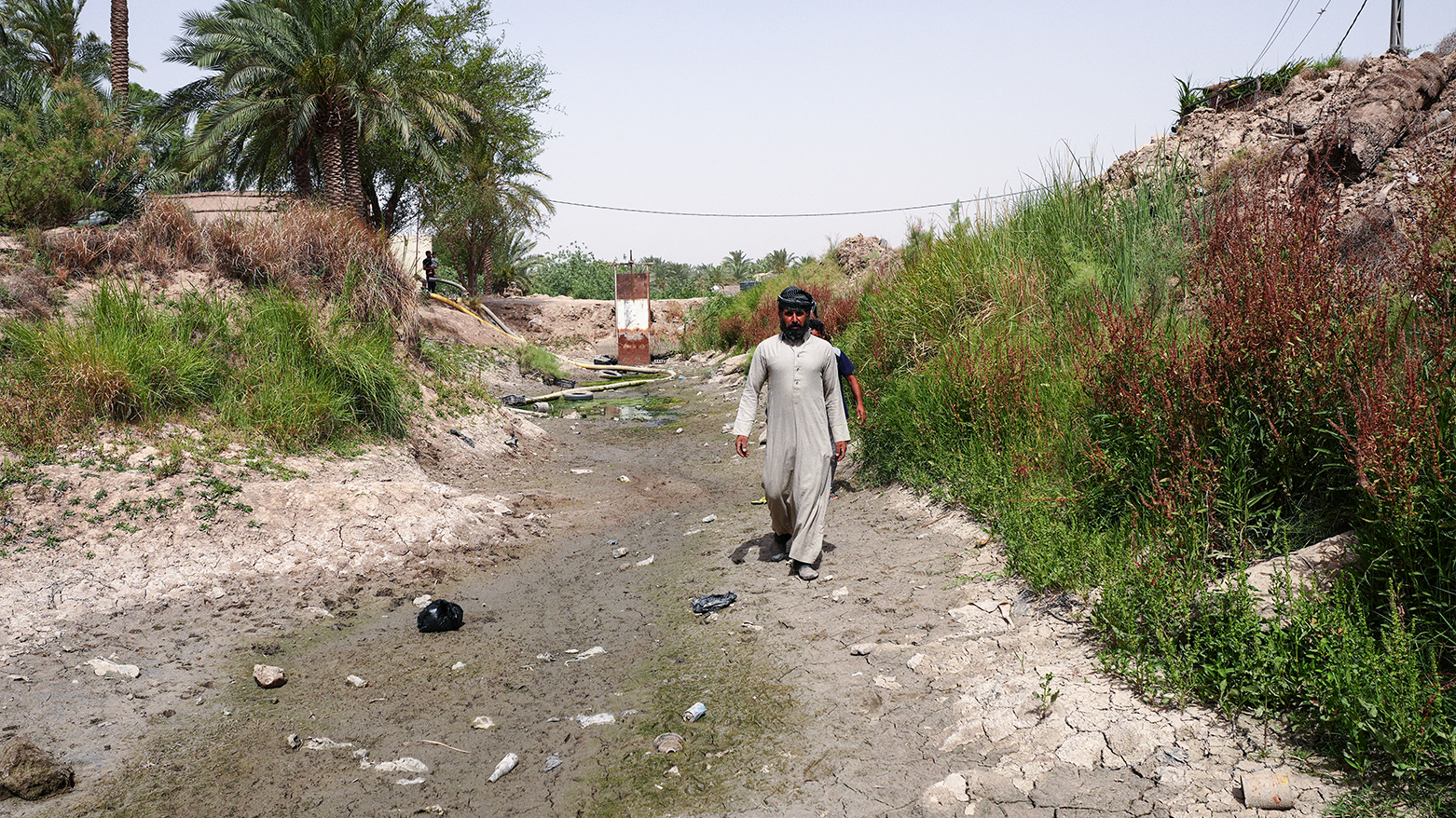 Men walk along a dried up stream in Mishkhab, in Iraq's Najaf province on May 24, 2025. (Photo: AFP)