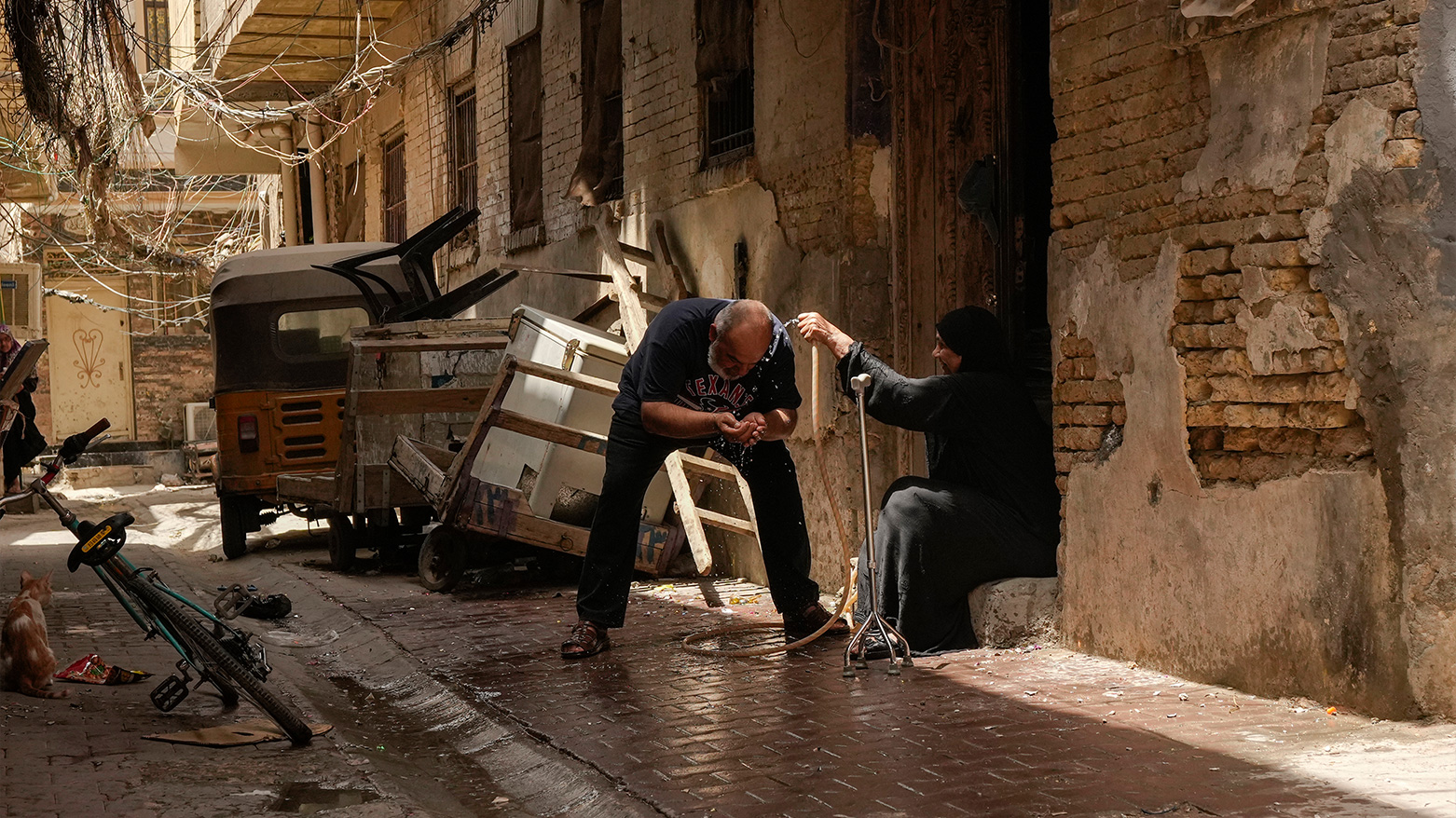A woman spray a man with a water hose during a heat wave outside his home in the al Fadhil neighborhood in Baghdad, Iraq, July, 6, 2023. (Photo: AP)