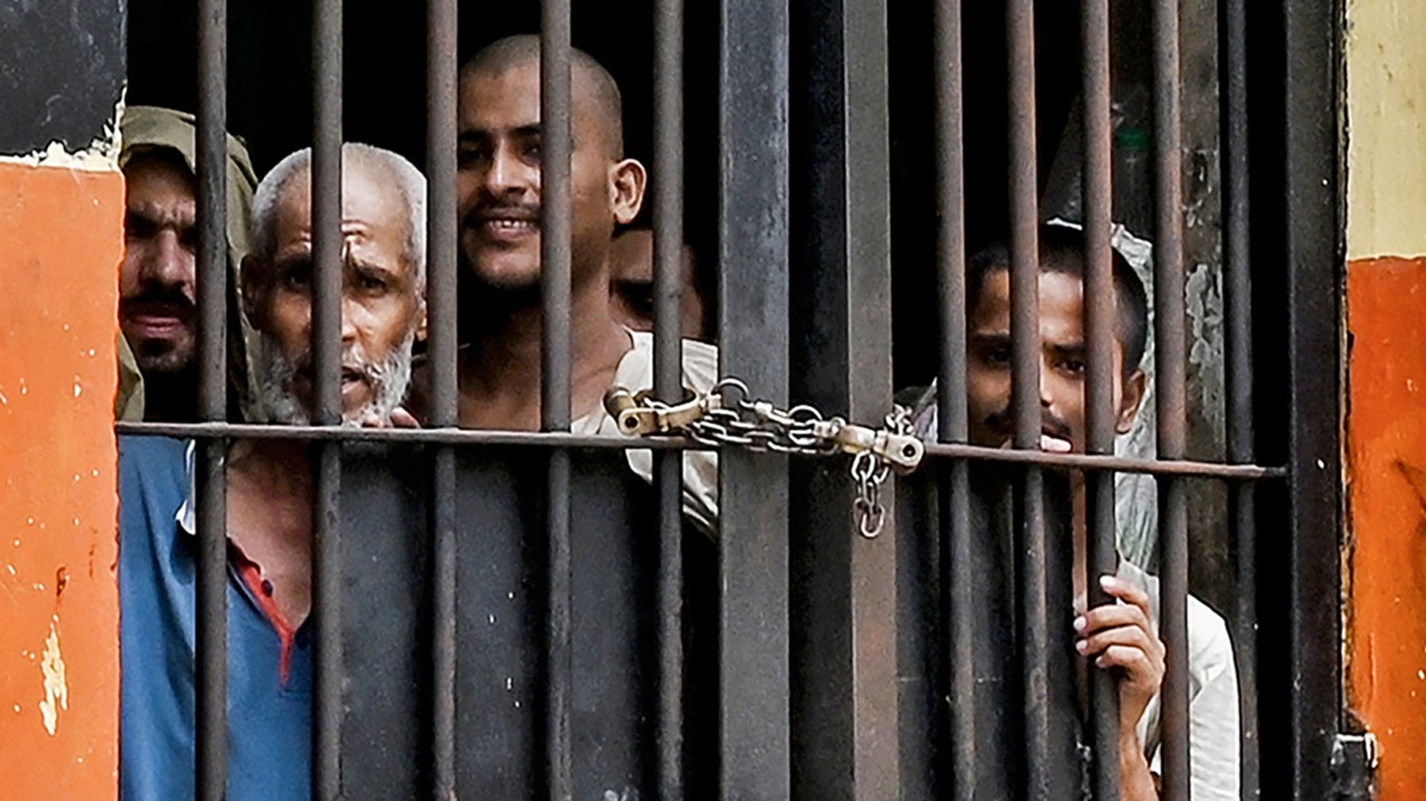 ينظر السجناء من خلال قضبان السجن المغلقة بالأصفاد بسبب كسر مزلاجها (فرانس برس)
