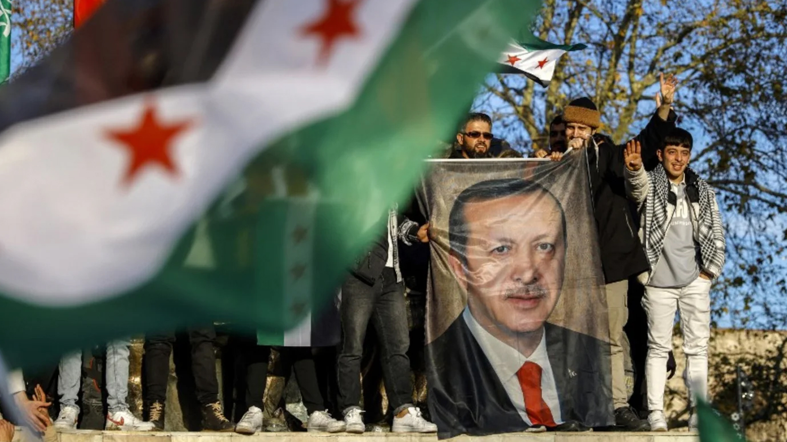 People hold a banner featuring Turkish President Recep Tayyip Erdogan as members of the Syrian community and supporters gather to celebrate the fall of Syrian president Bashar al-Assad In Istanbul's Fatih district on Dec. 8, 2024. (Photo: AFP)