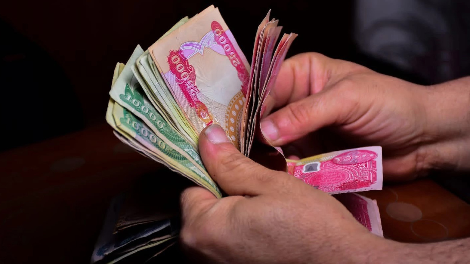A citizen counts cash money. (Photo: Kurdistan24)