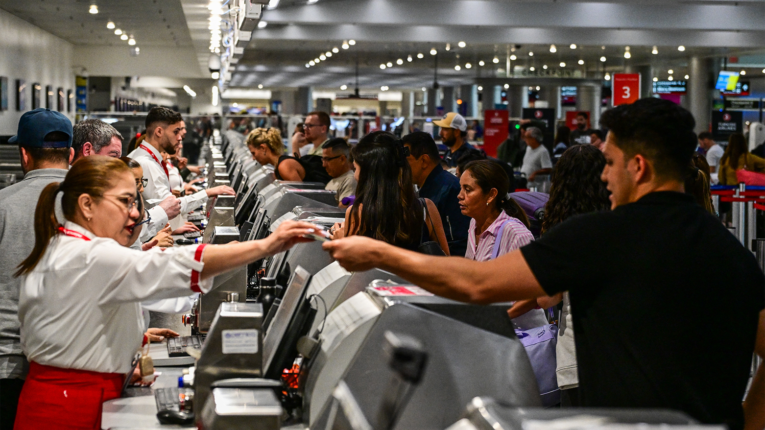 Travelers hand documents to airline staff at Miami International Airport on May 24, 2025 in Miami, Florida. (Photo: AFP)