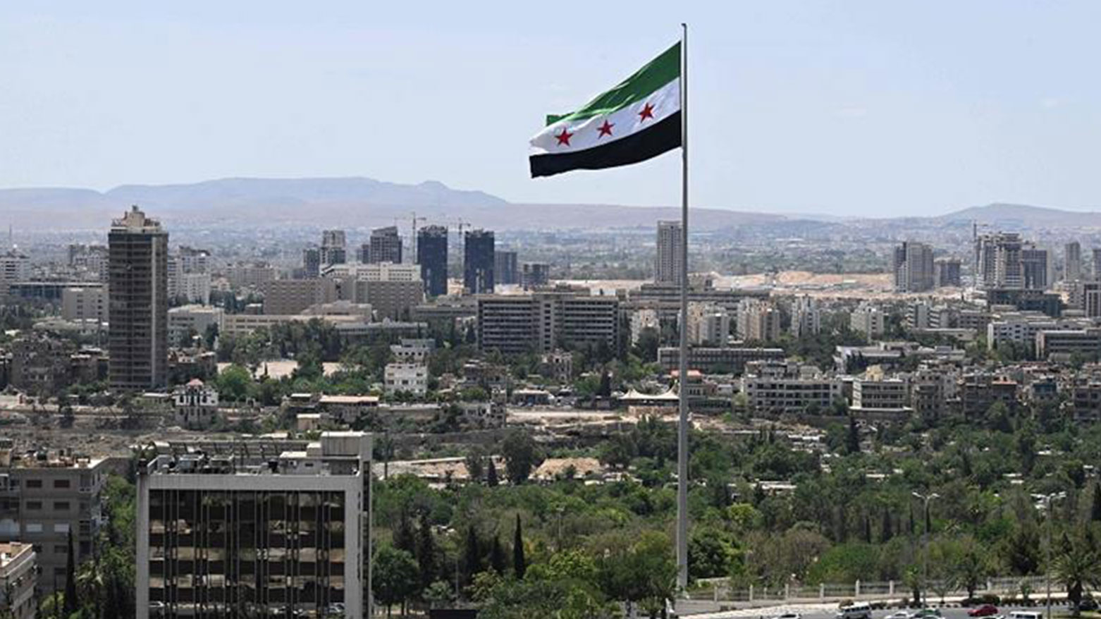 A large Syrian flag flutters above Tishreen Park in Damascus. (Photo: AFP)