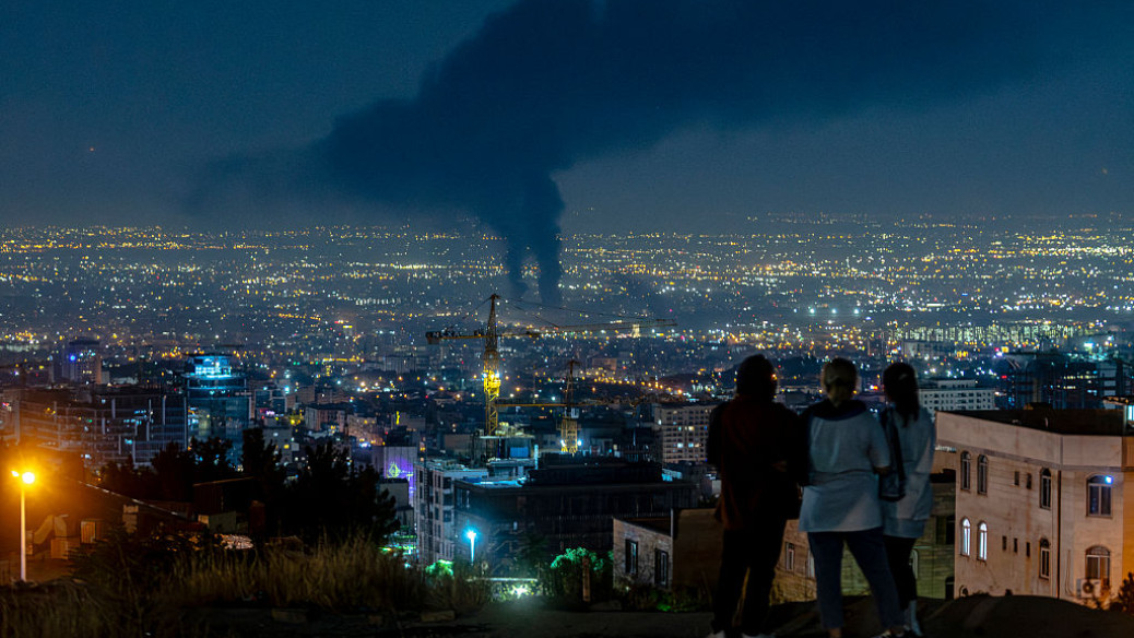 Iranians watch smoke rising in the distance from an Israeli airstrike in Tehran on 14 June 2025. (Photo: Social Media)