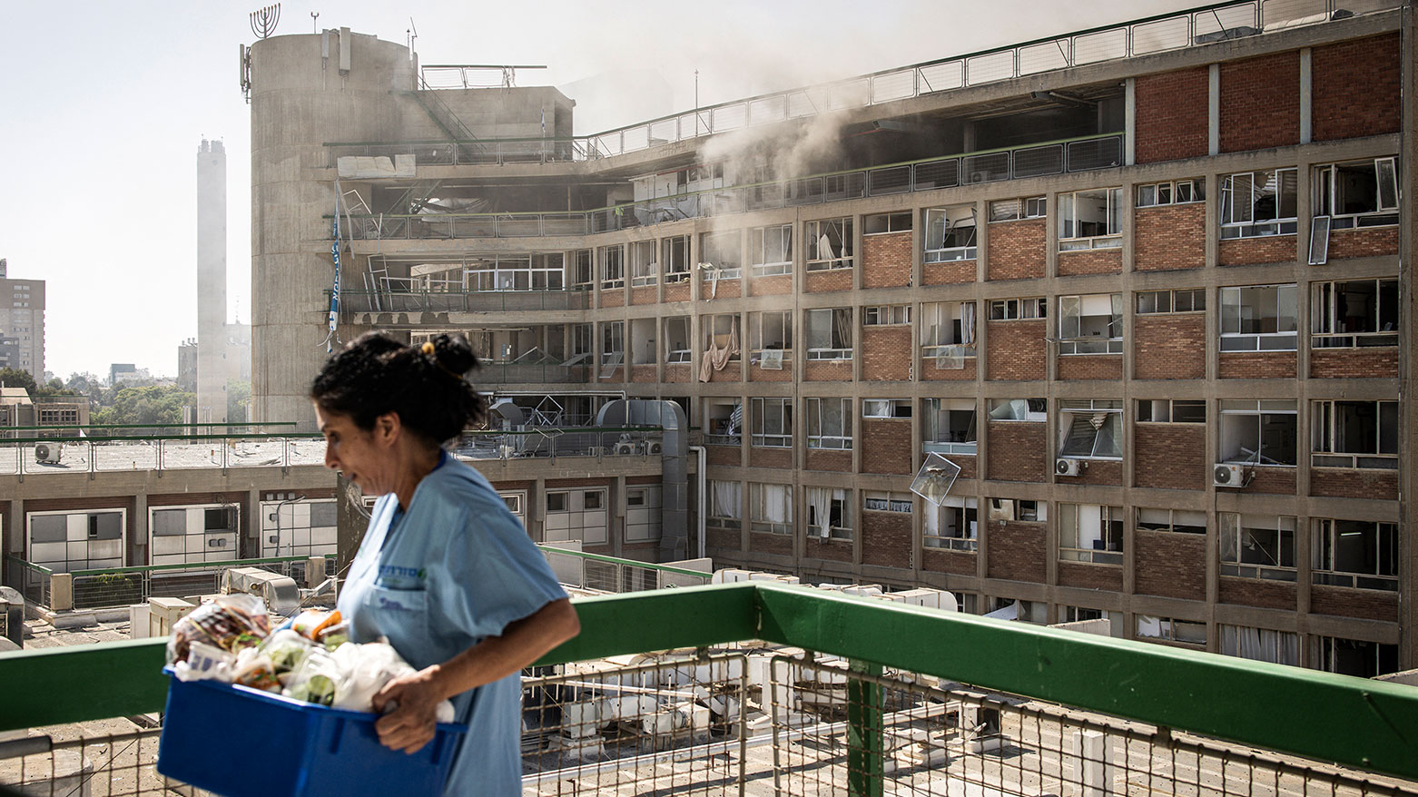 A nurse carries medical supplies past a building with smoke billowing out at Soroka Hospital following an Iranian missile attack in Beersheba in southern Israel on June 19, 2025. (Photo: AFP)
