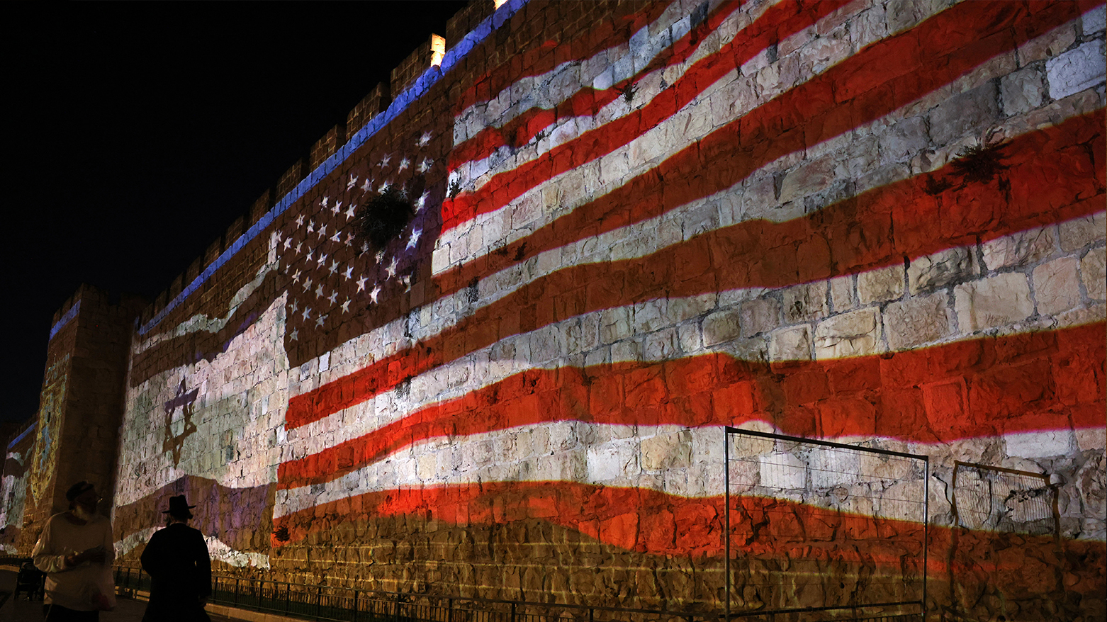 People walk past a projection depicting Israeli and US flags on the walls of Jerusalem's Old City on Jun. 22, 2025. (Photo: AFP)