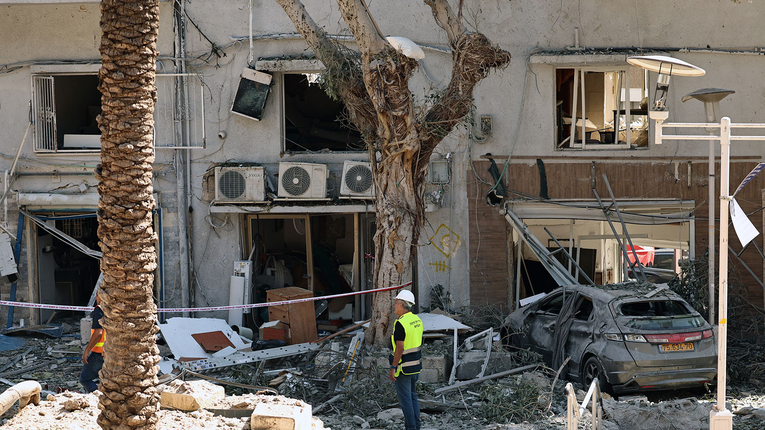 An Israeli first responder stands amid the rubble in front of a building hit during an Iranian strike in the port city of Haifa on June 22, 2025. (Photo: AFP)