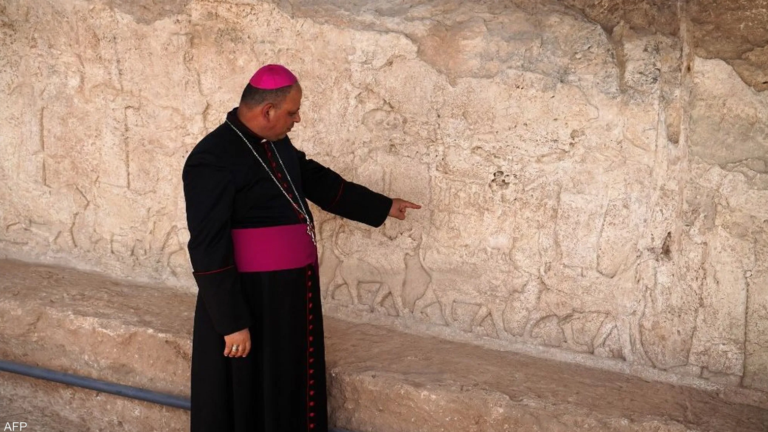 A cleric points to ancient Assyrian rock carvings of animals at the Fayda Archaeological Park in Dohuk, Kurdistan region. (Photo: Archive)
