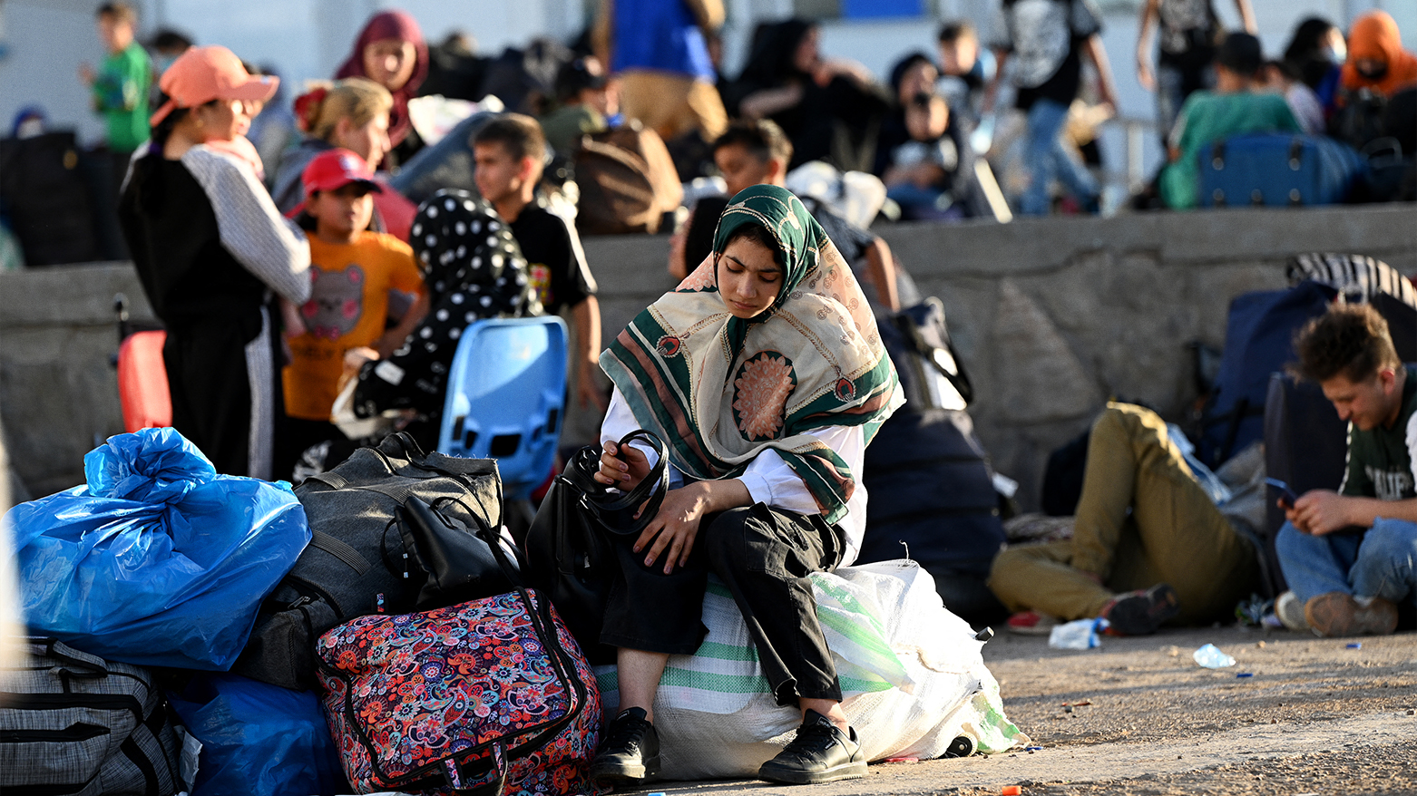 Afghan refugees rest with their belongings at the Islam Qala border after being deported from Iran, June 28, 2025. (Photo: AFP)
