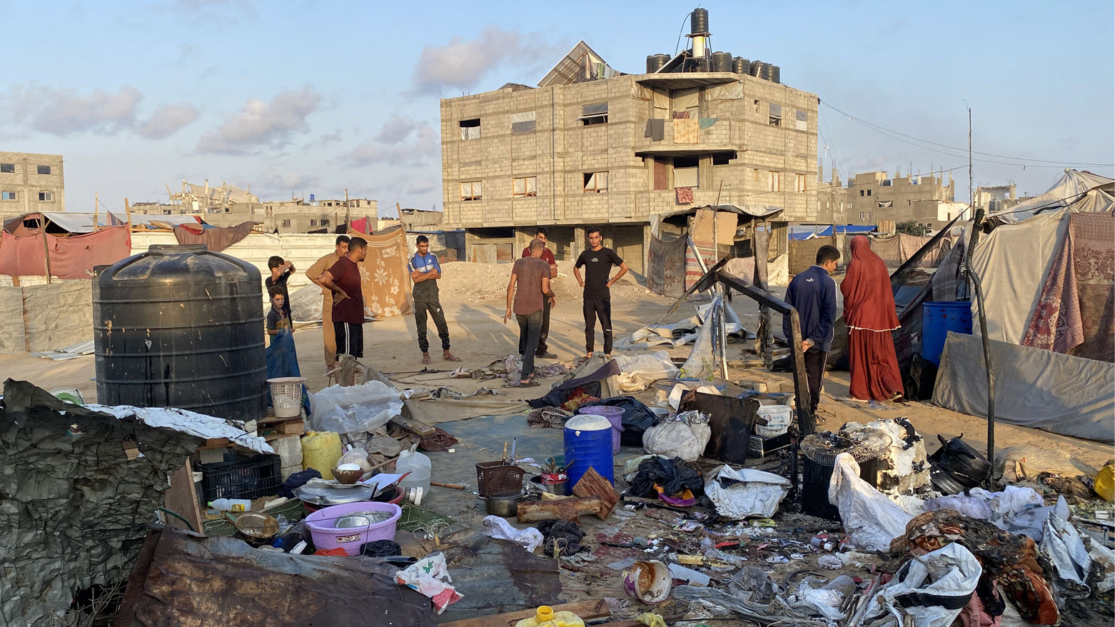 أشخاص يتفقدون الأضرار التي ألحقتها غارة إسرائيلية بمخيم للنازحين في خان يونس جنوب غزة (فرانس برس)