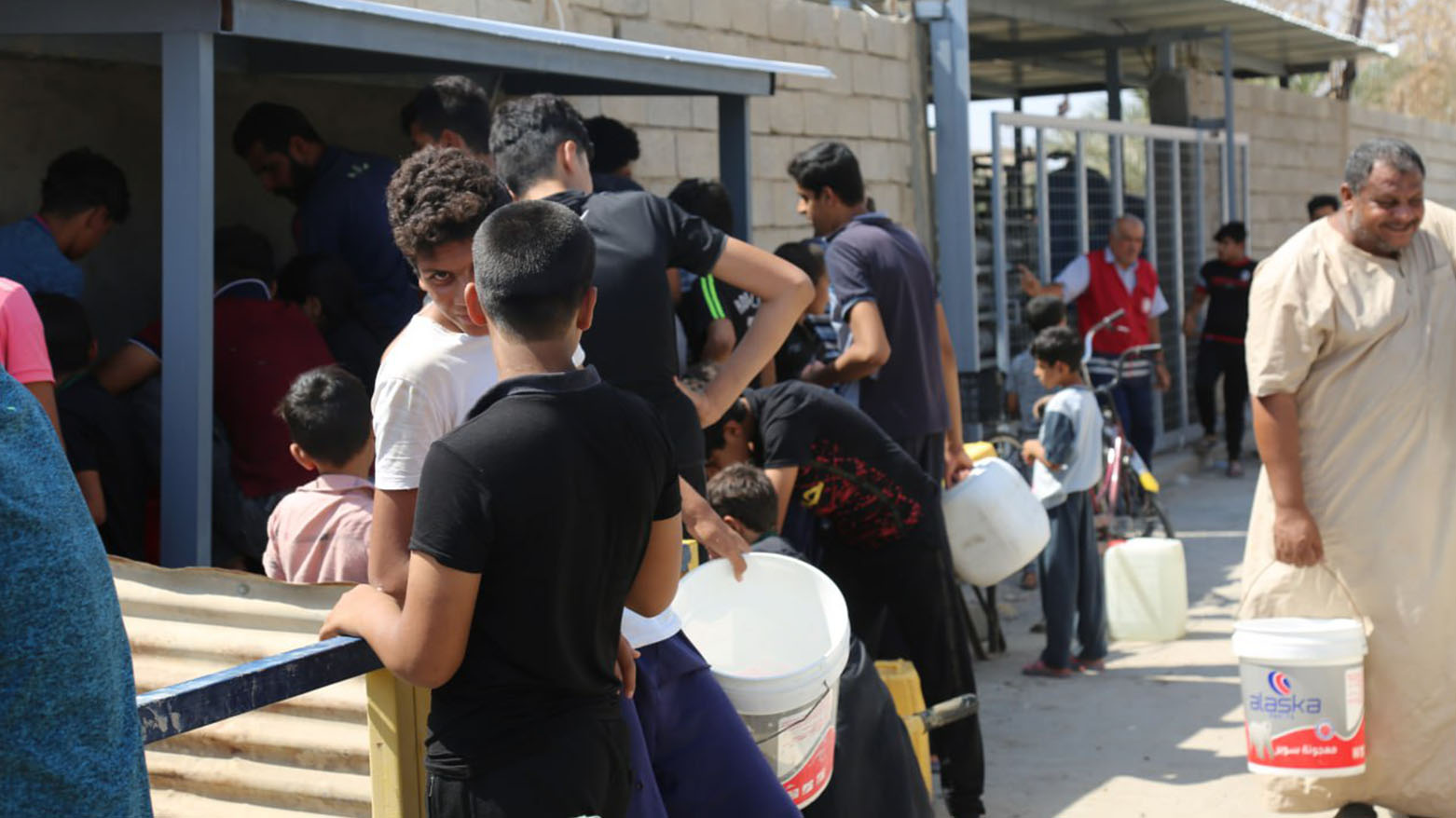 Crowd of people, waiting in line to get water, outside water desalination stations. (Photo: Iraqi Red Crescent)