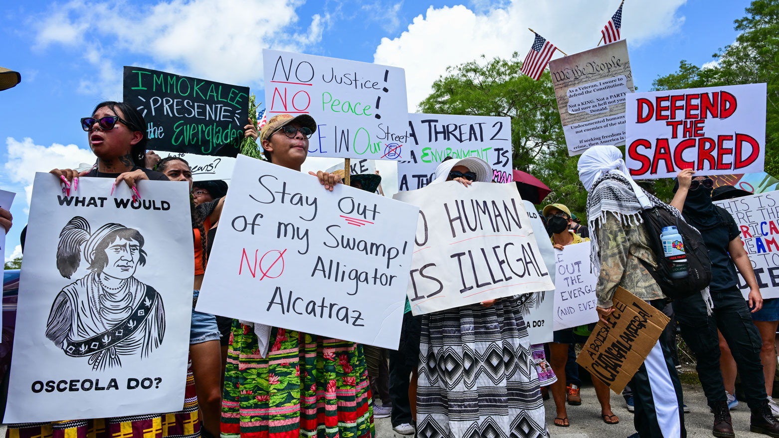 متظاهرون يحملون لافتات احتجاجًا على زيارة ترامب لمركز احتجاز المهاجرين (فرانس برس)