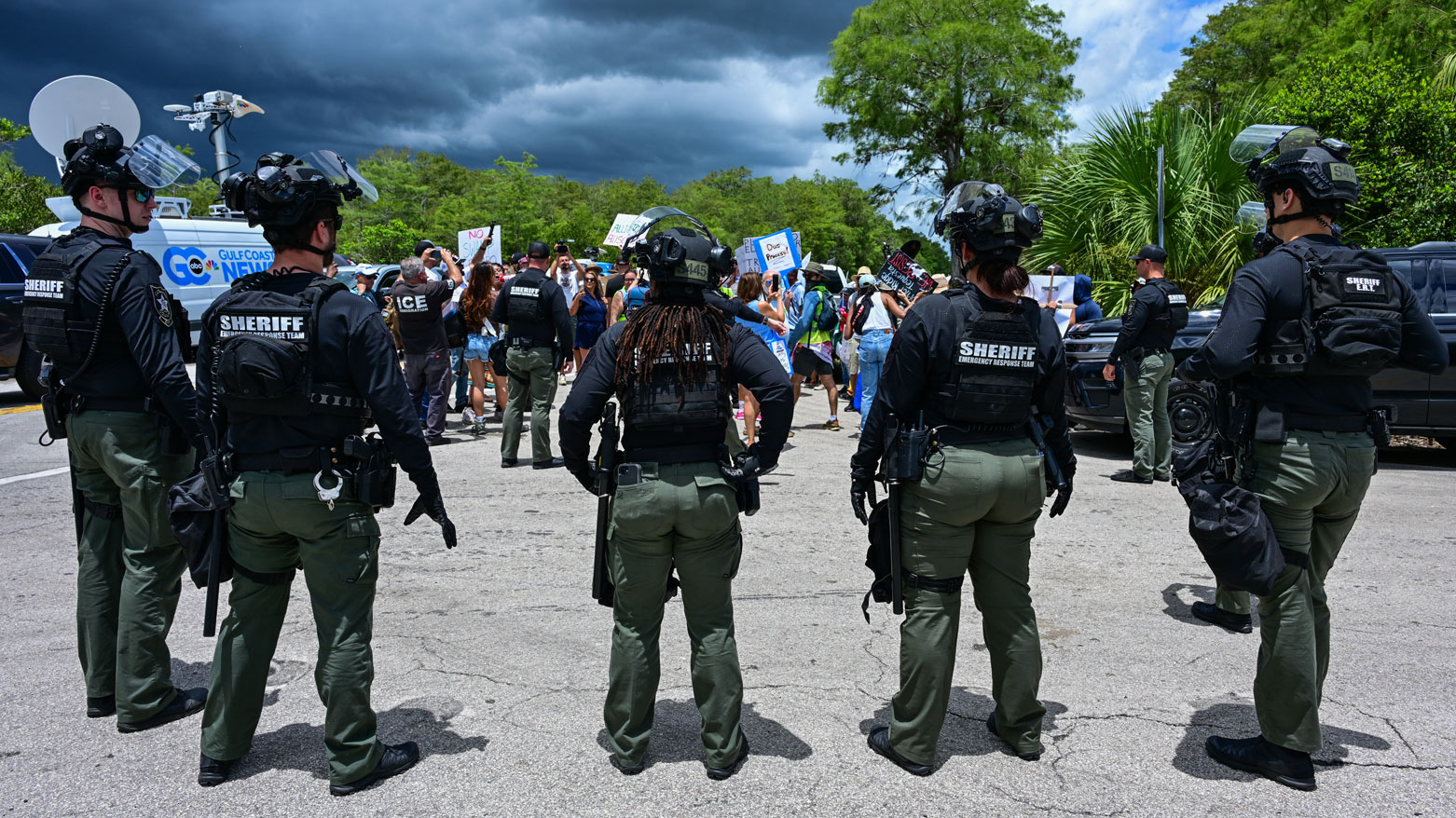 يقف رجال الشرطة حراساً بينما يحتج المتظاهرون على زيارة ترامب لمركز احتجاز المهاجرين (فرانس برس)