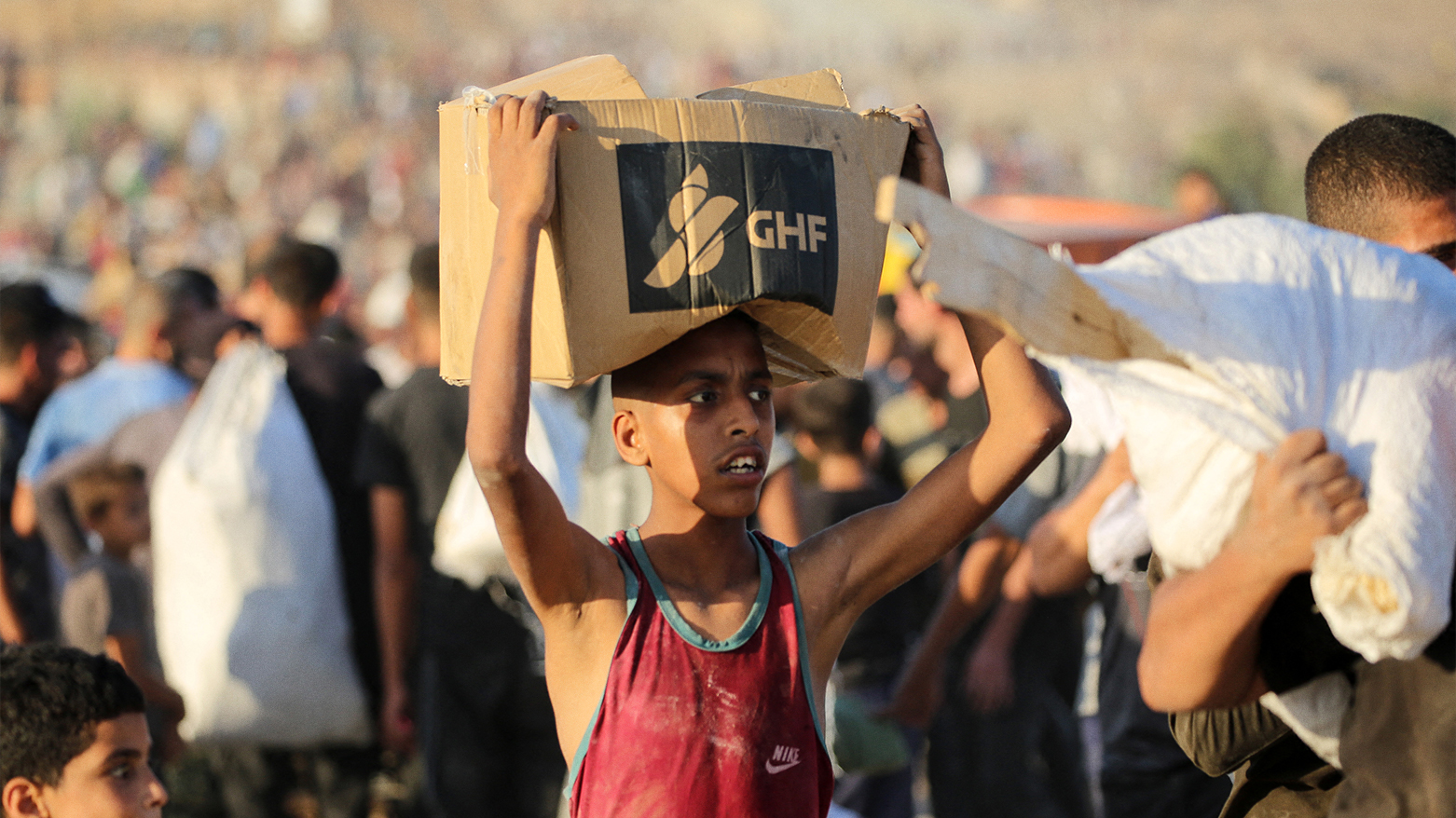 A youth carrying a GHF aid parcel, walks along the Salah al-Din road near the Nusseirat refugee camp in the central Gaza Strip. (Photo: AFP)
