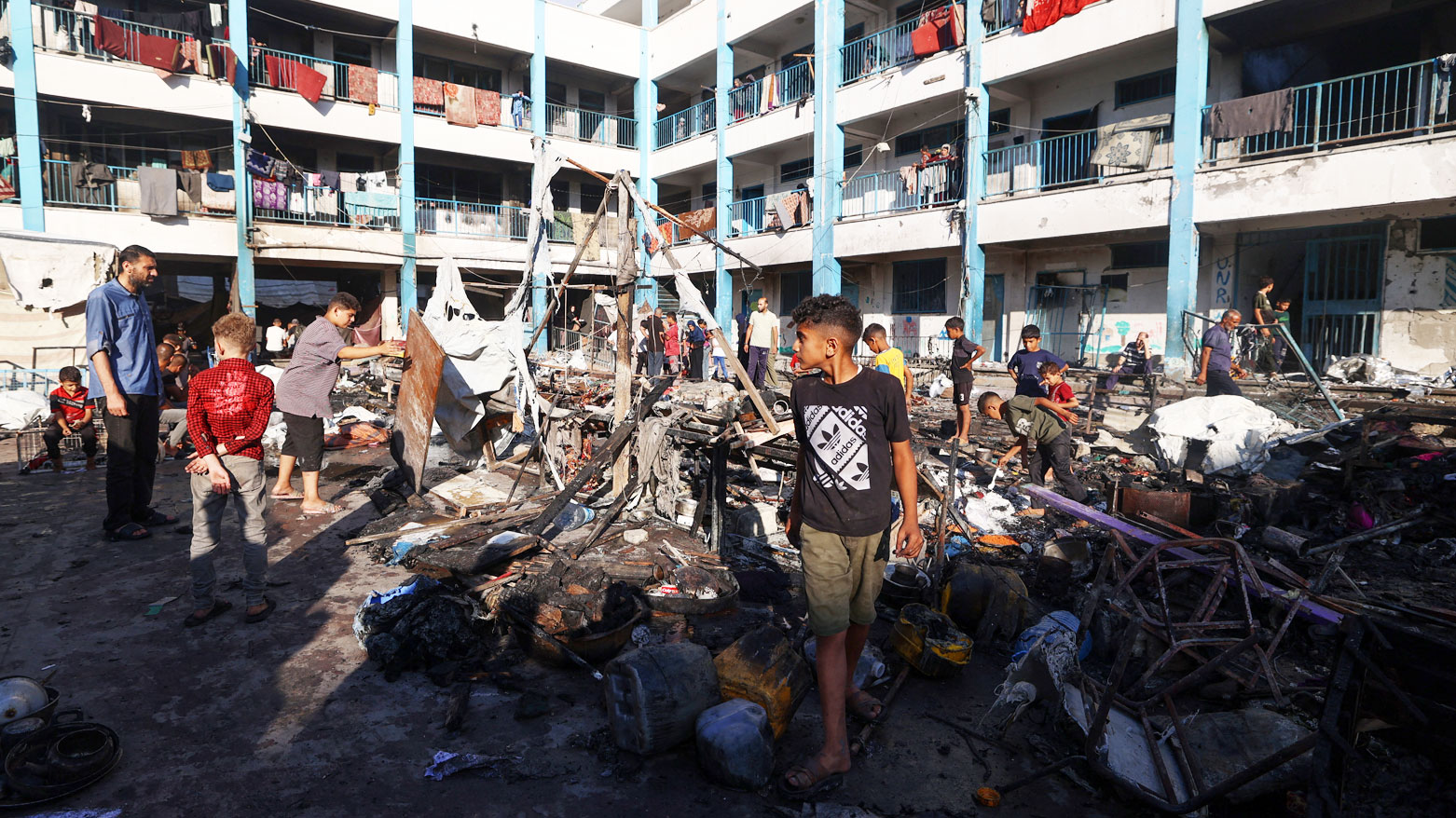 فلسطينيون يتفقدون الدمار الذي خلفته غارة إسرائيلية استهدفت مدرسةً تأوي نازحين في مخيم البريج بغزة (فرانس برس)