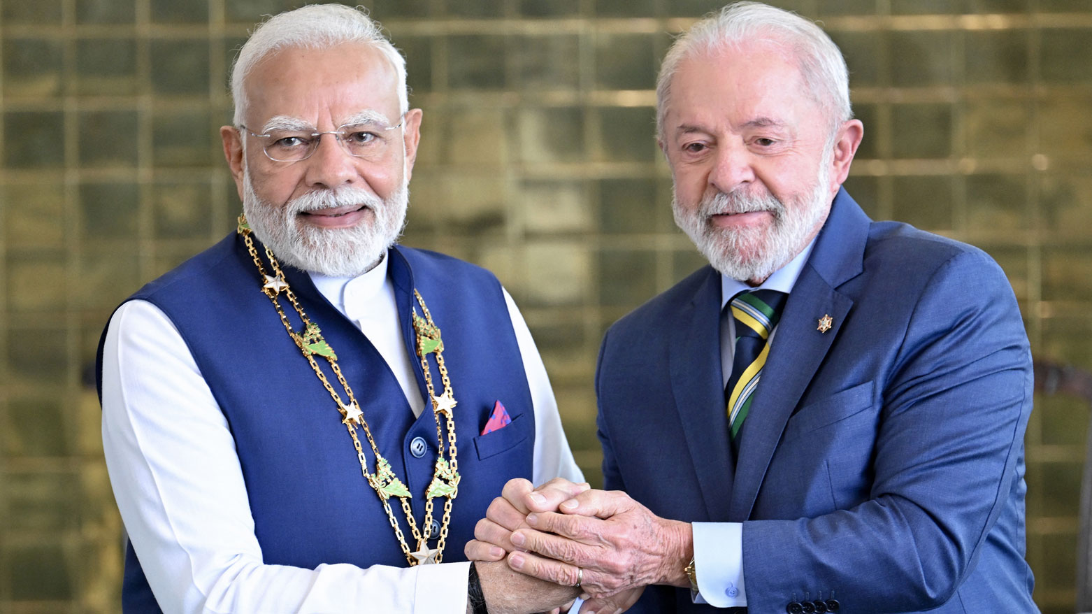 رئيس الوزراء الهندي يمسك يد الرئيس البرازيلي بعد حصوله على وسام الصليب الجنوبي الوطني في برازيليا (فرانس برس)