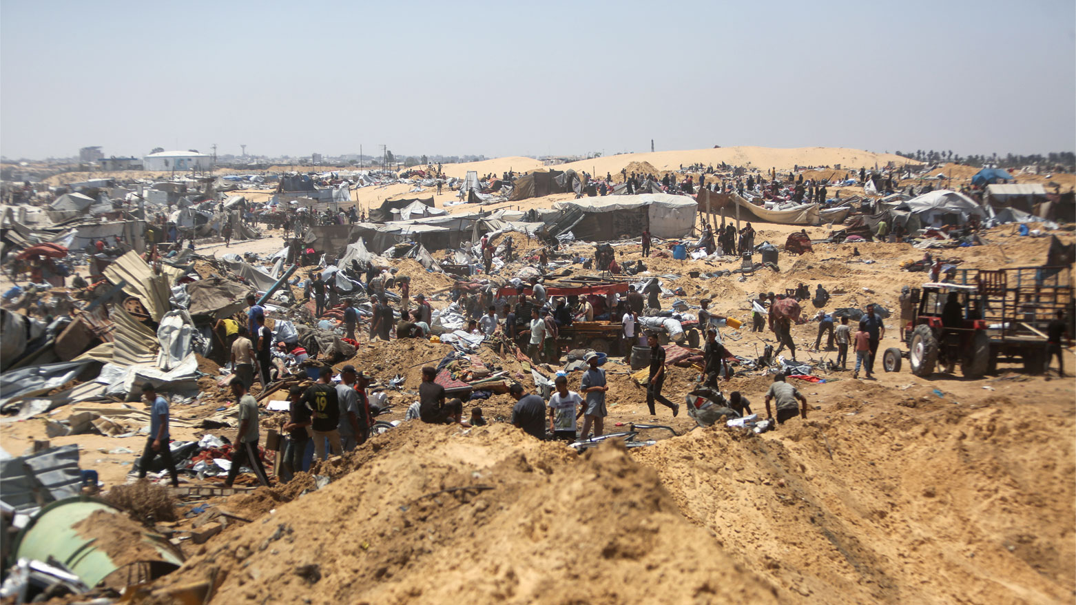فلسطينيون يتفقدون الدمار في مخيم نازحين مؤقت في خان يونس بقطاع غزة (فرانس برس)