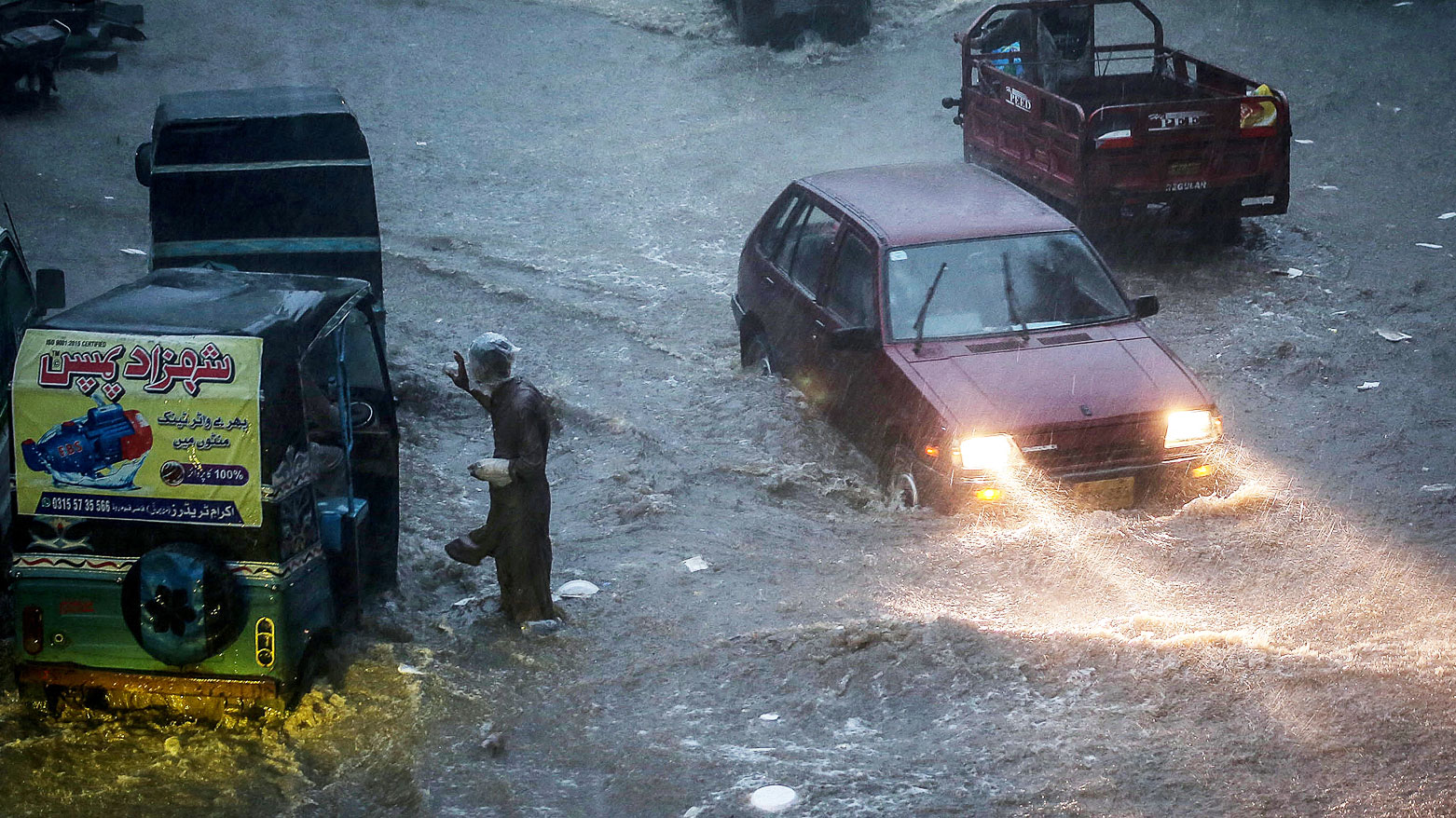 مسافرون يشقون طريقهم عبر طريق غمرته المياه في حيدر أباد- إقليم السند (فرانس برس)