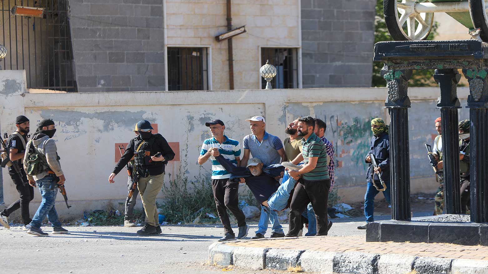 People carry a man wounded during clashes between Bedouin tribes and Druze fighters, near the predominantly Druze city of Sweida on July 14, 2025. (Photo: AFP)