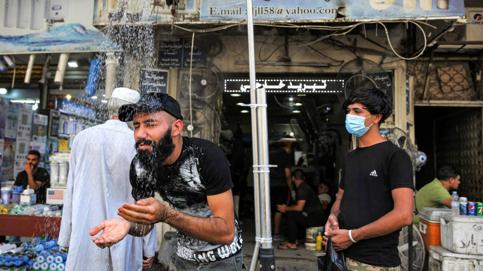 A man stands underneath a roadside shower along Sinak street in Iraq's capital Baghdad. (Photo: AFP)