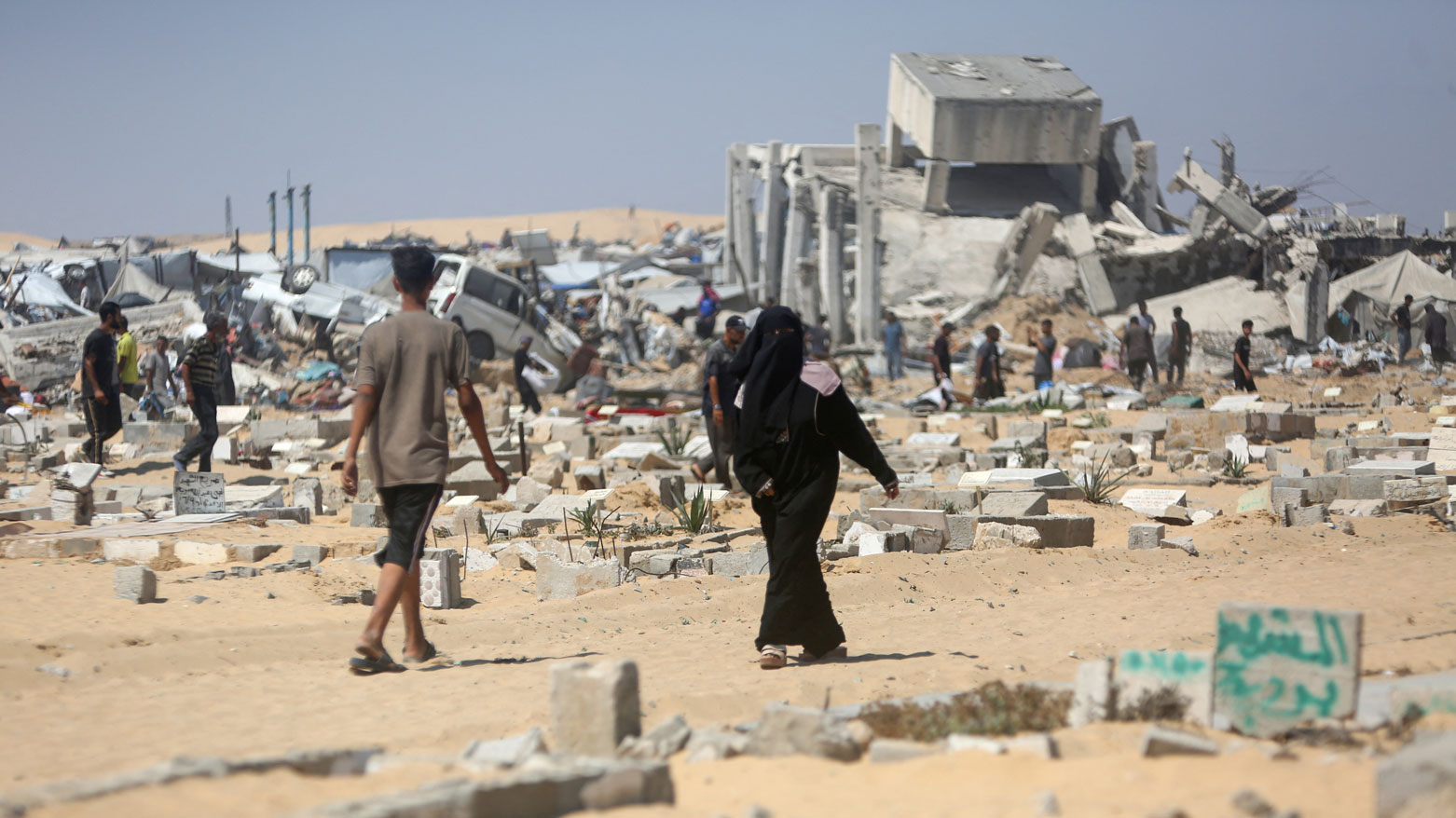 فلسطينيون يتفقدون الدمار في مخيم نازحين في خان يونس جنوب غزة (فرانس برس)