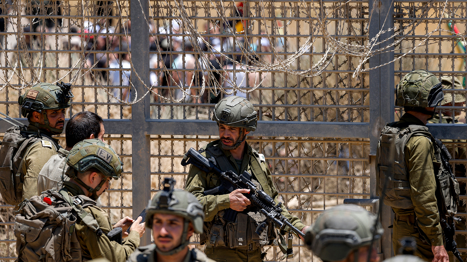 Israeli forces gather by the dividing line as members of Syria's Druze community gather on the other side attempting to cross the barbed-wire fence with the Israeli-annexed Golan Heights near Majdal Shams on Jul. 16, 2025. (Photo: AFP)