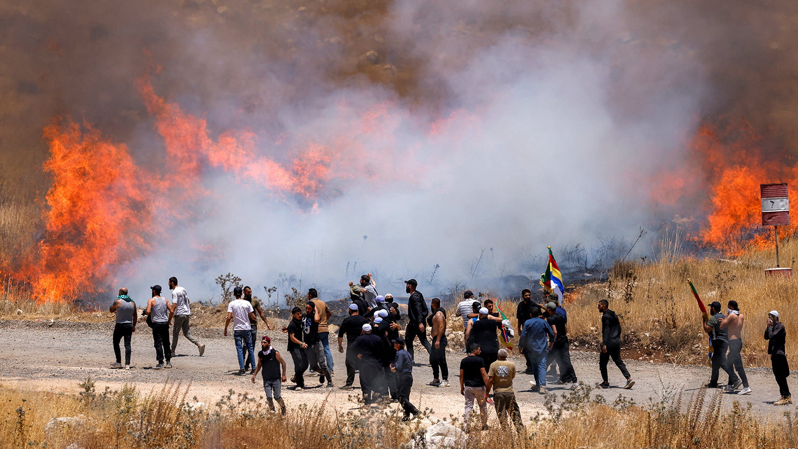 Members of Syria's Druze community walk through tear gas fumes, to attempt to cross the barbed-wire fence with the Israeli-annexed Golan Heights on Jul. 16, 2025. (Photo: AFP)