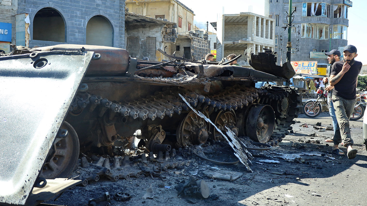Syrian Druze fighters walk near a damaged army military vehicle, after Syrian government forces pulled out of the southern Suwayda governorate, on July 17, 2025. (Photo: AFP)