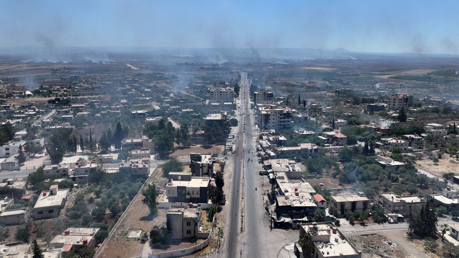 تصاعد الدخان فوق مبانٍ في قرية المزرعة بمحافظة السويداء جنوبي سوريا (فرانس برس)